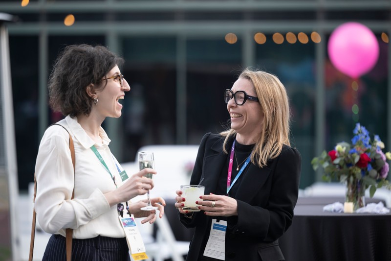 Two meeting attendees share a laugh and enjoy a beverage together.