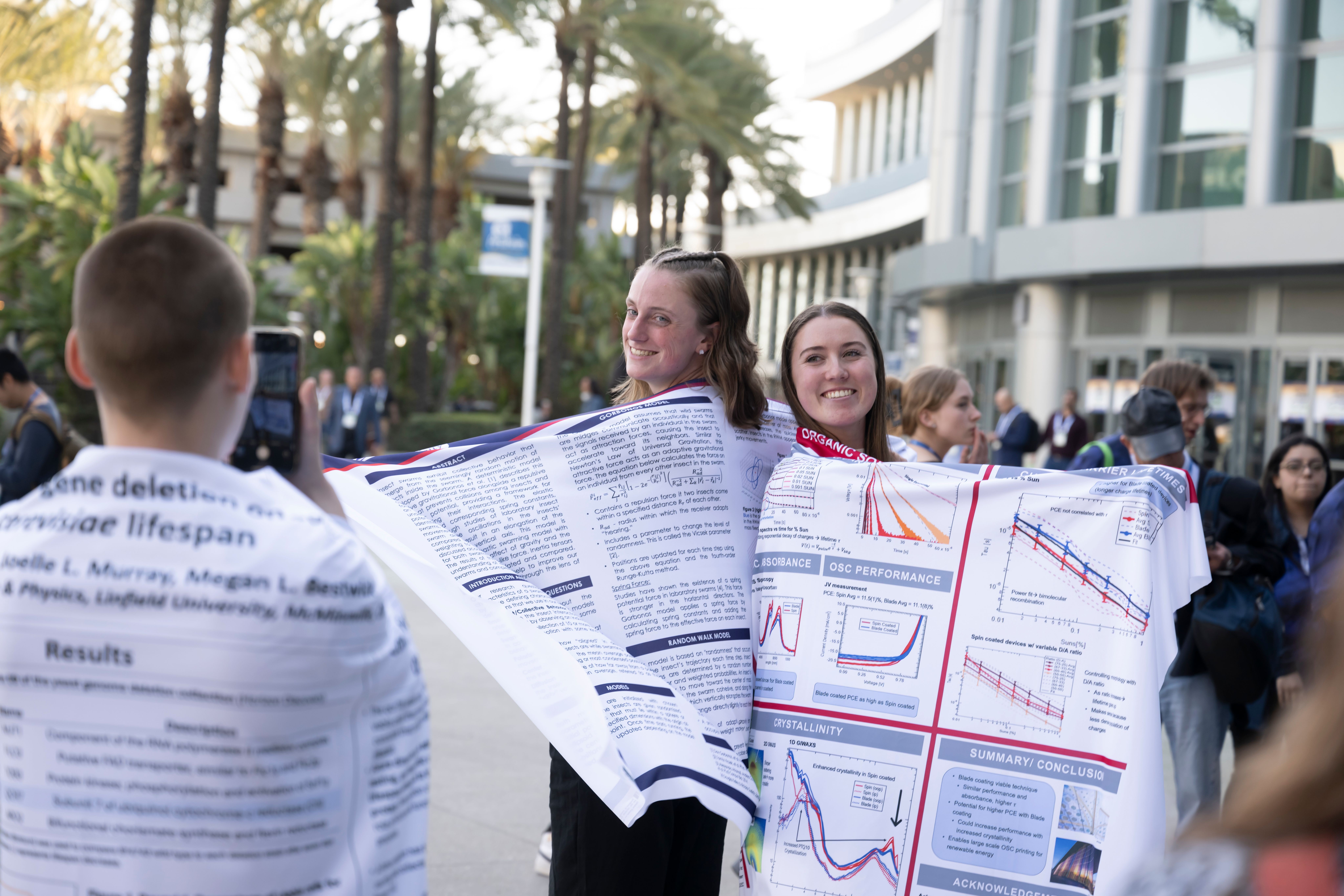 Meeting attendees cover themselves in enlarged APS website charts and text.